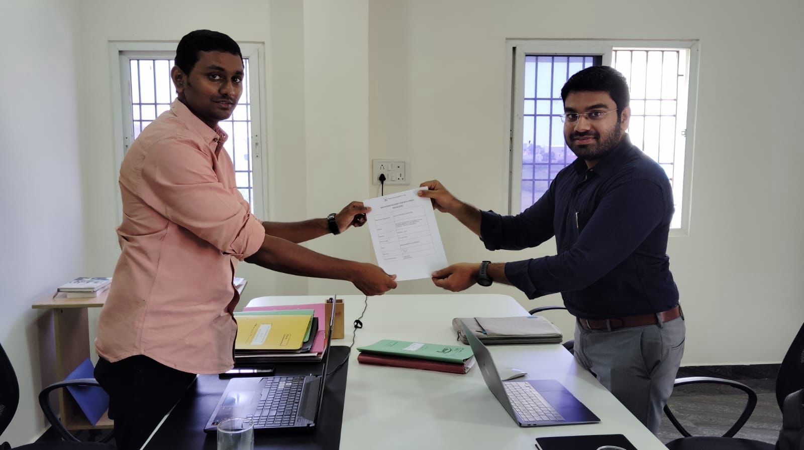 Impleton team handing over registration documents to a client at their office